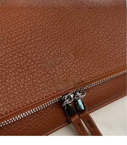 Gros plan d'un sac en cuir grainé marron avec fermeture éclair argentée et logo chic