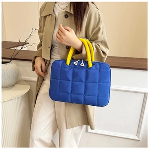 Close-up of quilted navy laptop bag with yellow handles and triangular metal zipper