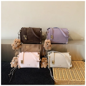 Group display of four colorful box bags with metal buckles and cute teddy bear charms
