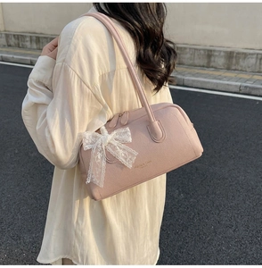Pink Boston bag with white lace bow detail and textured leather finish in outdoor setting