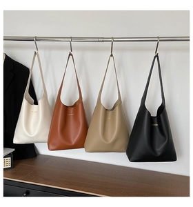 Row of large tote bags in cream, tan, khaki, and black colors hanging on a metal rack