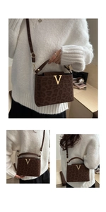 Detailed close-up of brown leopard print handbag with golden V-buckle and adjustable strap
