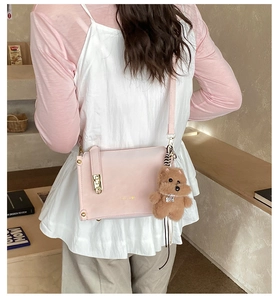 Pink leather baguette bag with golden buckle and plush bear charm shown on model
