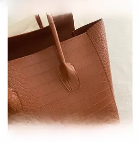 Detailed macro view of the warm brown crocodile pattern tote bag with reinforced handle stitching