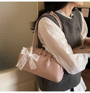 Vue détaillée du sac Boston rose avec un élégant nœud en dentelle blanche et cuir grainé