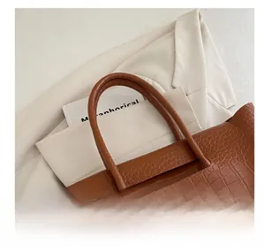 Detail of crocodile embossed leather tote bag with sturdy handles on office attire