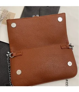 Détail du sac en cuir grainé marron avec chaîne argentée et fermoirs magnétiques ronds