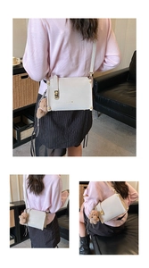 Detail of a beige crossbody bag featuring a plush bear charm and striped ribbon accent