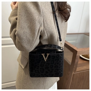 Detail of leopard print flocking fabric and gold V-shaped metal clasp on crossbody bag