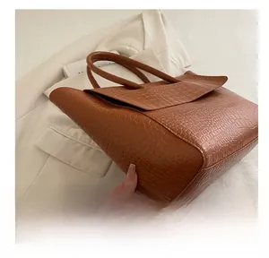 Detail of brown tote bag with premium faux crocodile texture on a white background
