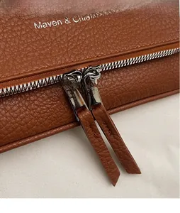 Détail du sac en cuir marron à motif litchi avec double fermeture éclair et tirettes longues