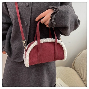 Détail du sac à main en daim bordeaux avec bordure en sherpa blanche tenu par un mannequin
