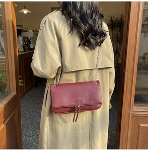 Dettaglio borsa a tracolla bordeaux in pelle martellata con catena e nappe argentate