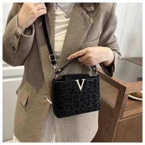 Detail of black leopard print crossbody bag with gold V-shaped buckle on sueded fabric
