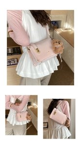 Detail of pink crossbody bag with gold hardware and a cute plush bear charm accessory