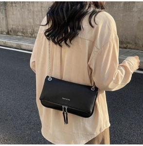 Dettaglio della borsa a catena in pelle nera con cerniere e logo Maven & Chic