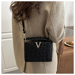 Detail of black leopard print crossbody bag with gold V-shaped buckle and fine velvet texture