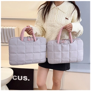 Close-up of quilted grey laptop bag with pink handles and triangular zipper pull details