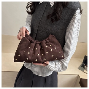 Vue détaillée de la pochette en daim marron foncé avec rivets dorés et design plissé