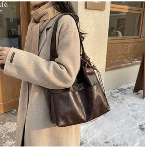 Detail of dark brown glossy tote bag with stylish lock charm and decorative scarf