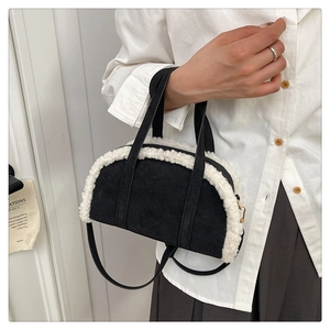 Détail du sac en daim noir avec bordure en peau de mouton blanche et fermeture dorée
