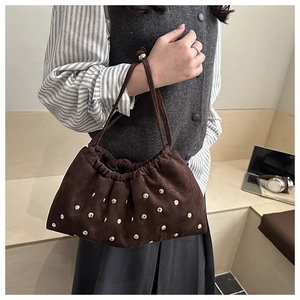 Détail du sac vintage en daim marron avec rivets dorés et fermeture à cordon plissée