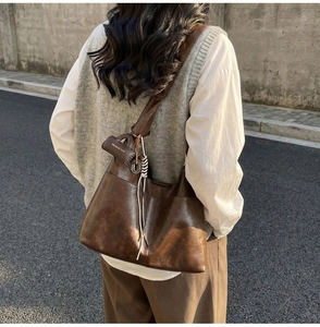 Detail of vintage brown tote bag with mini pouch charm and braided strap on shoulder