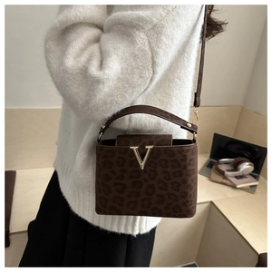Detail of leopard print crossbody bag with gold V-hardware in a casual lifestyle setting