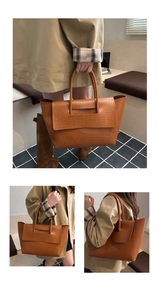 Detailed view of the orange-brown crocodile texture and handle on a large tote bag