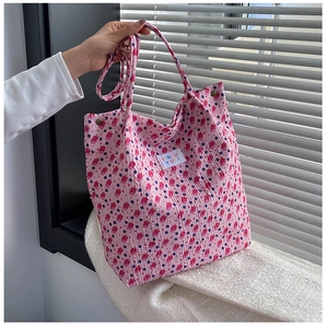 Close-up of pink floral tote bag fabric with red dots and JANYUN YCAI metal logo