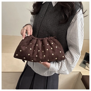 Détails de la pochette nuage en daim marron foncé ornée de rivets métalliques dorés