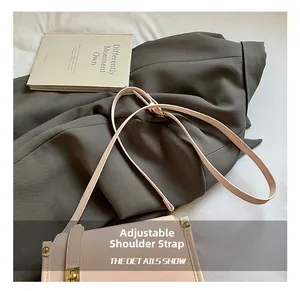 Detail showing the adjustable thin shoulder strap and golden metal buckle on the light beige bag