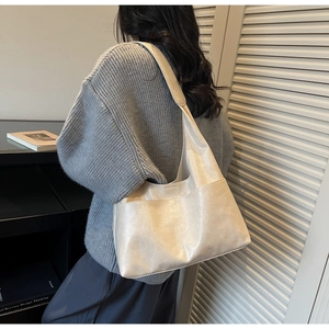 Side view of large off-white leather hobo bag with spacious pockets on shoulder