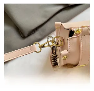 Detail of pink box bag showing light gold metal hardware and brown plush pendant