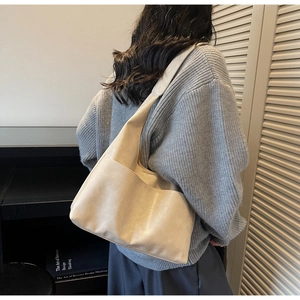 Detail of the large beige hobo bag with a side pocket worn by a model in casual style