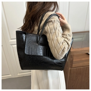 Close-up of black crocodile pattern tote bag with large capacity held by a model