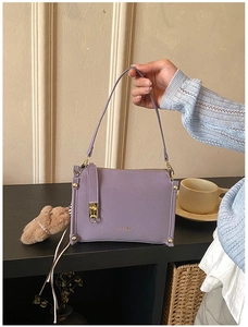 Detail of purple leather box bag with gold metal clasp and brown plush rabbit charm