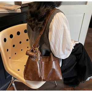 Detail of vintage brown tote bag featuring a mini pouch charm with white tassels
