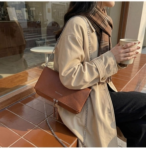 Close-up of brown litchi pattern leather bag with silver chain strap and fringe detail