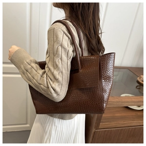 Detailed view of the dark brown crocodile embossed texture on a large tote bag