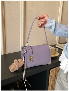 Detail of purple PU leather box bag with gold buckle and cute brown bear charm