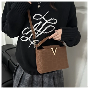 Detail of leopard print handbag with golden V buckle and adjustable shoulder strap