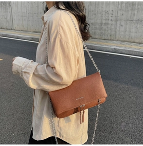 Brown litchi pattern leather crossbody bag with silver chain strap shown on model