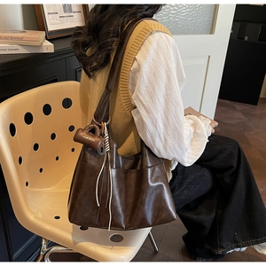 Detail of soft brown leather hobo bag with mini decorative pouch on shoulder strap