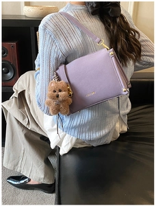 Purple leather box bag with a cute teddy bear charm shown from a high-angle perspective
