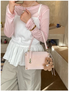 Detailed shot of pink faux leather handbag featuring golden lock and brown bear charm