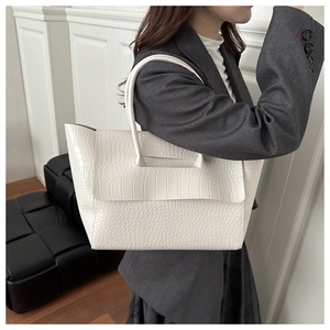 Detailed view of white crocodile pattern tote bag with flap and long handle shown on model