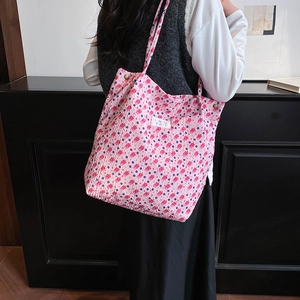 Pink floral canvas tote bag with colorful polka dots shown on a model's shoulder