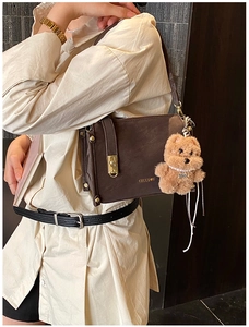 Detail of dark brown retro crossbody bag with gold lock and plush bear charm