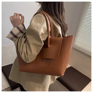 Brown tote bag with crocodile texture shown on shoulder for professional women